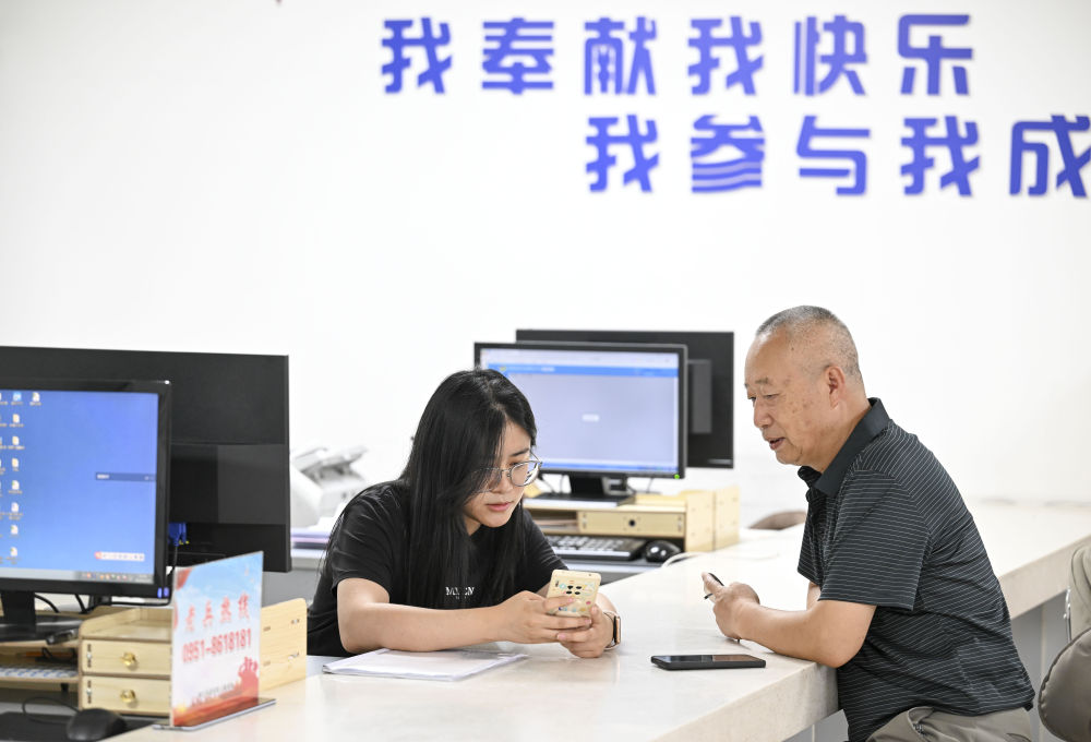 2024年6月20日，在寧夏銀川市金鳳區(qū)長城花園社區(qū)黨群服務中心，工作人員幫助居民辦理業(yè)務。圖片來源 新華社